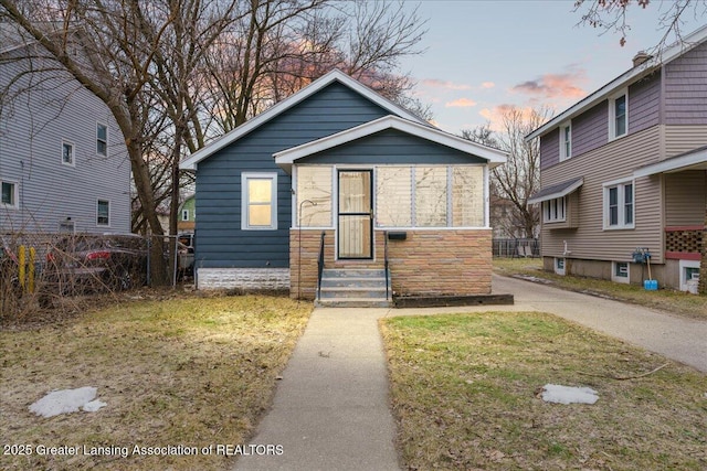 bungalow-style house featuring entry steps, a front yard, and fence