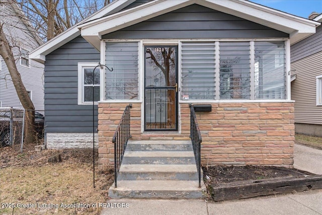 view of front of home with stone siding and fence