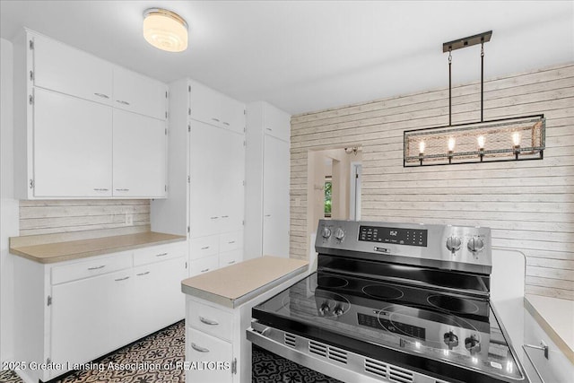 9840 W Herbison Rd, Eagle, MI 48822 - kitchen with electric stove, light countertops, white cabinetry, and wood walls