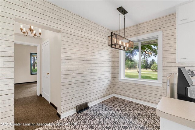 9840 W Herbison Rd, Eagle, MI 48822 - unfurnished dining area with a chandelier and wooden walls