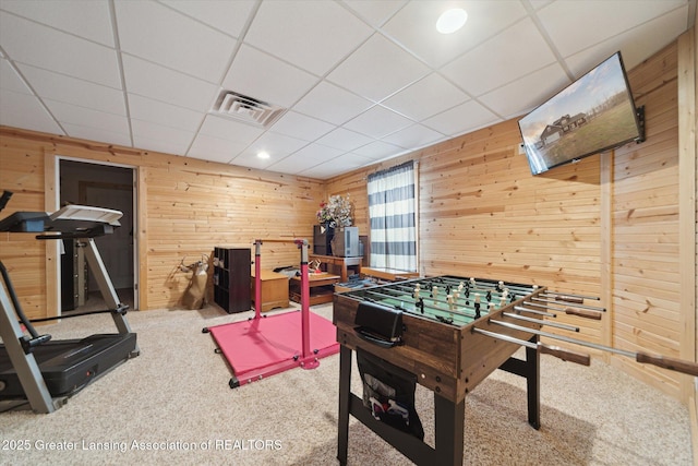 playroom featuring a paneled ceiling, visible vents, wood walls, and carpet flooring