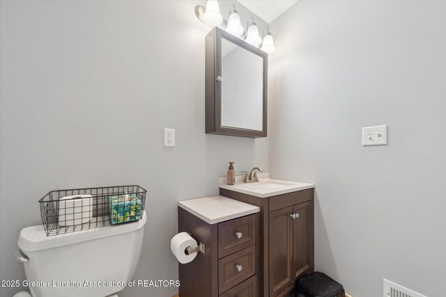 half bath featuring visible vents, vanity, and toilet