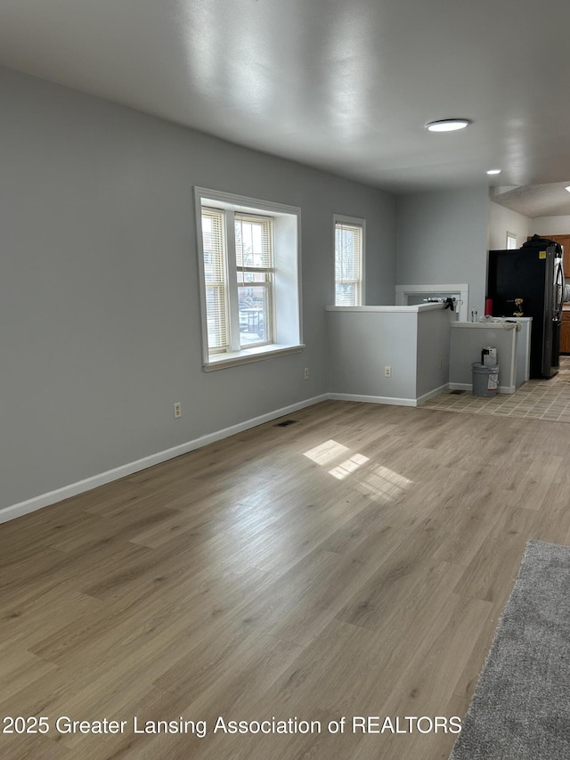 unfurnished living room featuring baseboards and light wood-style floors