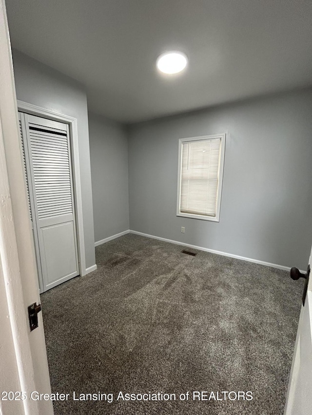 unfurnished bedroom featuring carpet floors, a closet, and baseboards