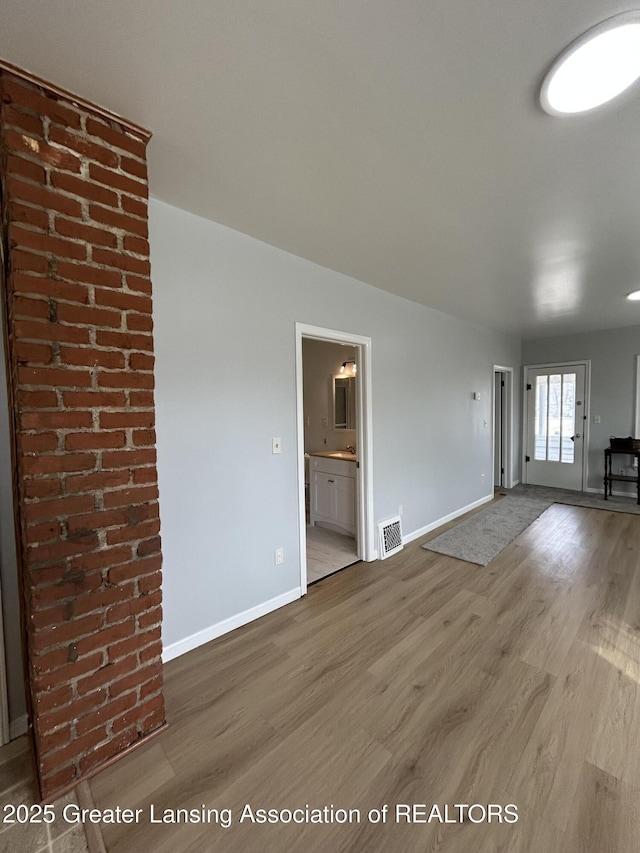 unfurnished living room featuring visible vents, baseboards, and wood finished floors