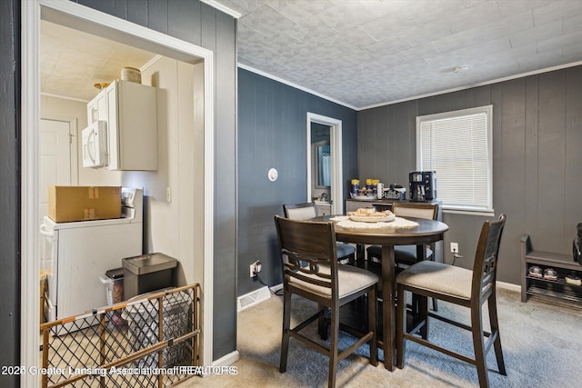 dining space featuring baseboards, crown molding, and light colored carpet