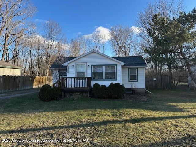 bungalow-style home with a front lawn and fence