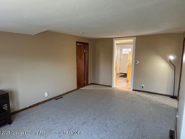 spare room with carpet, visible vents, and baseboards