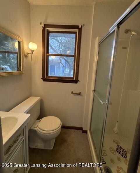 full bathroom with a stall shower, baseboards, vanity, and toilet