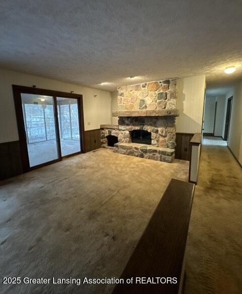 living room with a textured ceiling, a fireplace, and carpet flooring