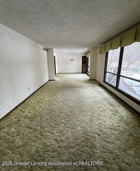 unfurnished room with carpet flooring, a textured ceiling, and baseboards