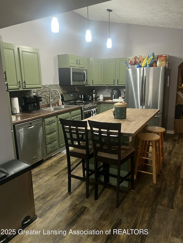 kitchen with dark wood-style flooring, stainless steel appliances, tasteful backsplash, green cabinets, and a sink