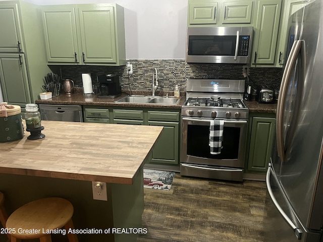 kitchen with decorative backsplash, green cabinetry, stainless steel appliances, wooden counters, and a sink