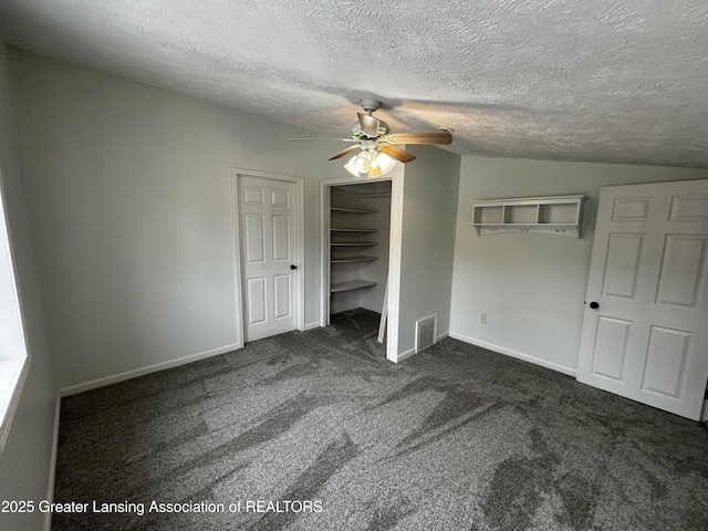 unfurnished bedroom featuring baseboards, visible vents, vaulted ceiling, a textured ceiling, and carpet flooring