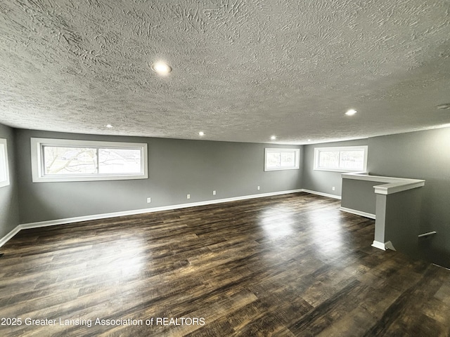 unfurnished room with a wealth of natural light, dark wood-style flooring, and baseboards