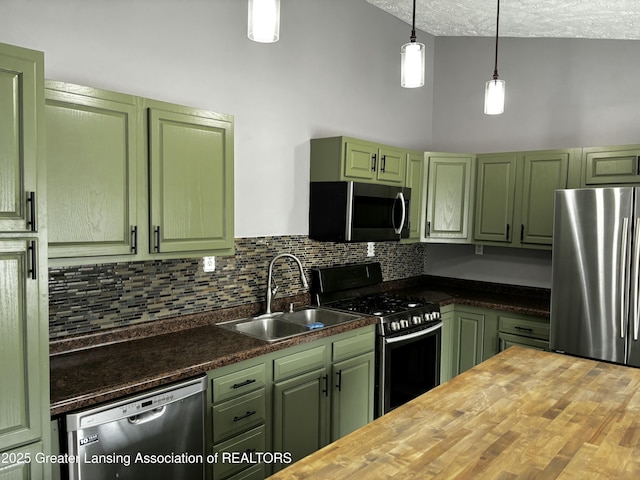 kitchen featuring butcher block countertops, a sink, green cabinets, appliances with stainless steel finishes, and decorative backsplash