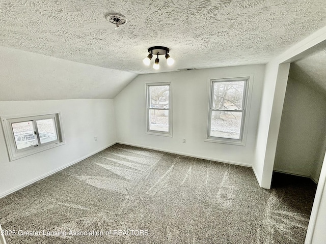 bonus room with a textured ceiling, carpet flooring, visible vents, baseboards, and vaulted ceiling