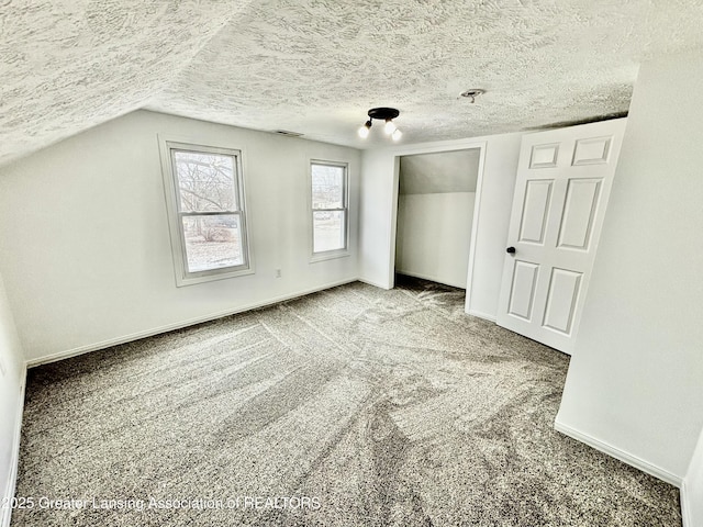 unfurnished bedroom with carpet, lofted ceiling, visible vents, a textured ceiling, and baseboards