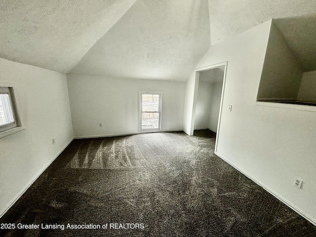 bonus room featuring a textured ceiling, carpet floors, lofted ceiling, and baseboards