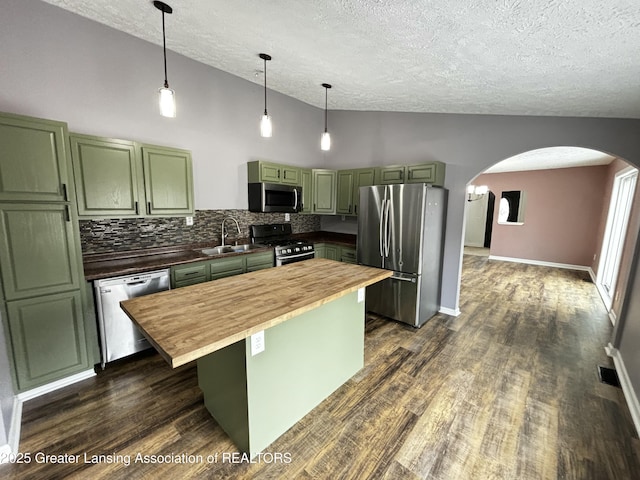 kitchen featuring green cabinetry, butcher block counters, vaulted ceiling, stainless steel appliances, and a sink