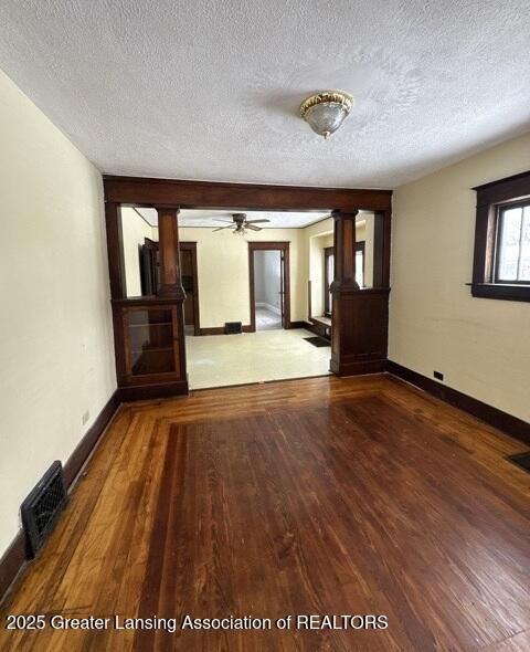 unfurnished room with wood finished floors, visible vents, and baseboards