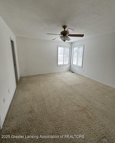 carpeted empty room with a ceiling fan and a textured ceiling