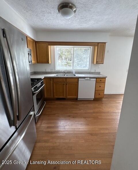 kitchen featuring a sink, brown cabinetry, stainless steel appliances, and wood finished floors