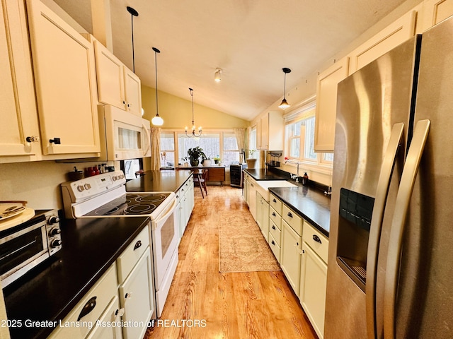 kitchen with dark countertops, an inviting chandelier, a sink, light wood-type flooring, and white appliances