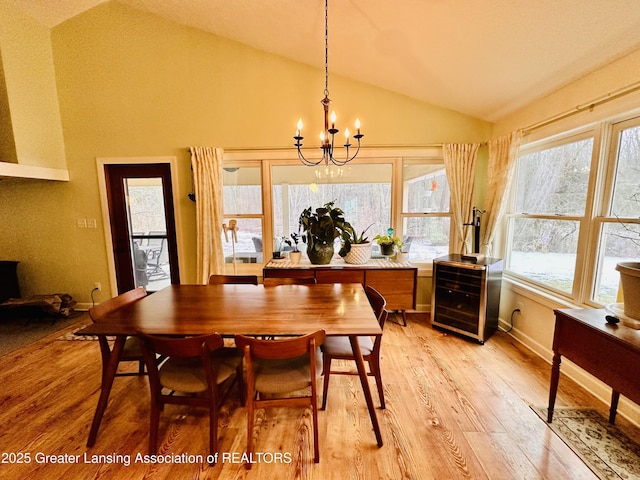 dining room featuring vaulted ceiling, light wood-type flooring, a chandelier, and baseboards