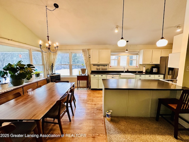 kitchen featuring light wood-type flooring, dark countertops, white cabinetry, and lofted ceiling