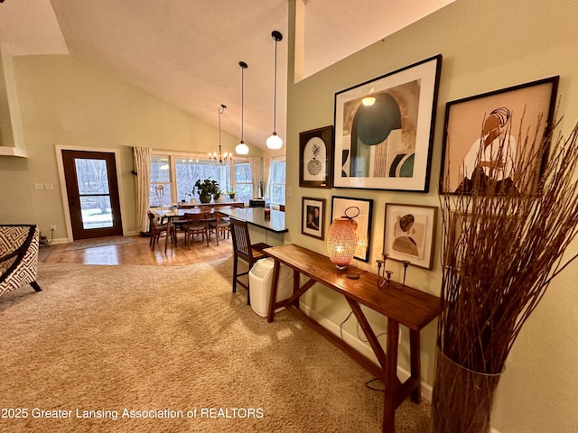 corridor featuring a chandelier, carpet, high vaulted ceiling, and baseboards