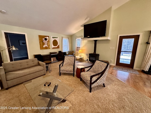 living room with high vaulted ceiling, a wood stove, and baseboards