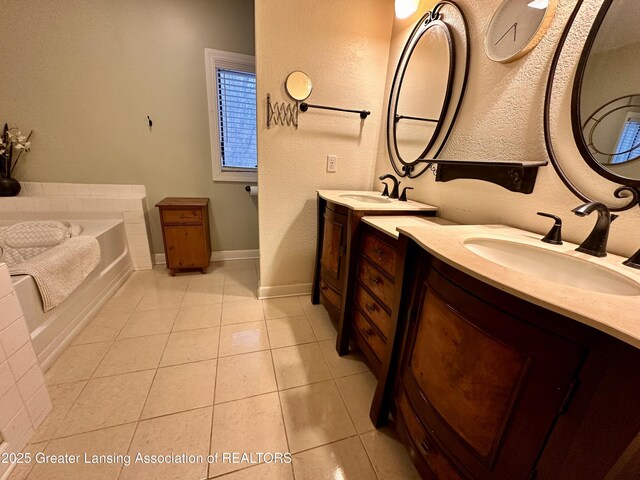 bathroom featuring tile patterned flooring, two vanities, a sink, and a bath