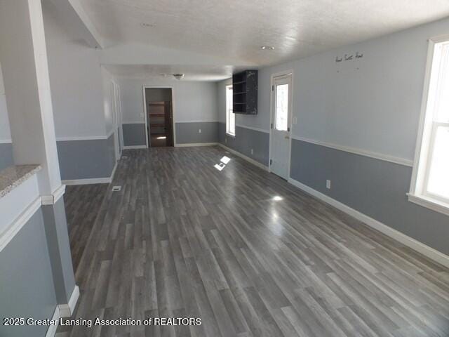 unfurnished living room featuring dark wood-style floors and baseboards