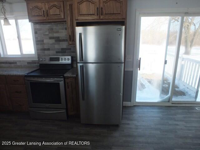 kitchen with appliances with stainless steel finishes, dark wood finished floors, and backsplash