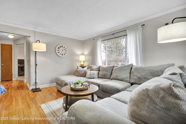 living area with crown molding, light wood-style flooring, and baseboards