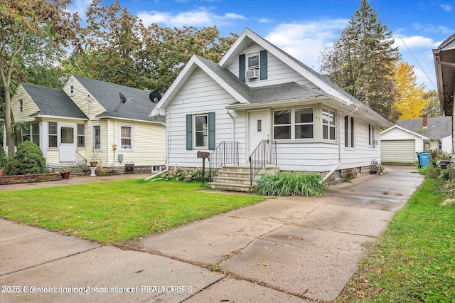 bungalow-style home with a shingled roof, a garage, an outdoor structure, and a front lawn