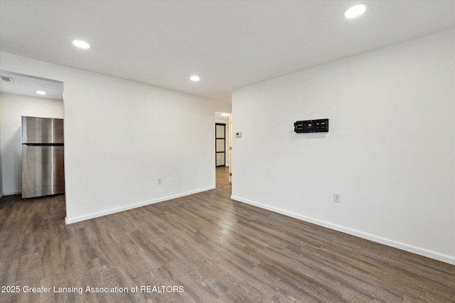 empty room featuring baseboards, wood finished floors, visible vents, and recessed lighting