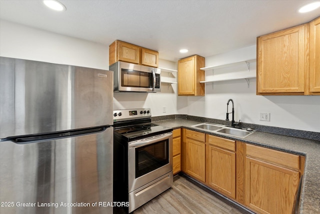 kitchen featuring recessed lighting, stainless steel appliances, a sink, open shelves, and dark countertops