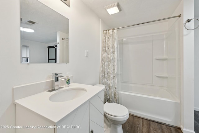 bathroom with toilet, wood finished floors, vanity, visible vents, and shower / tub combo with curtain