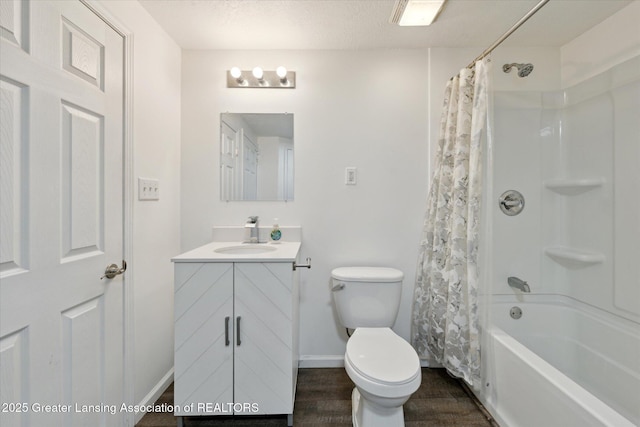 bathroom with toilet, wood finished floors, vanity, baseboards, and shower / bath combo