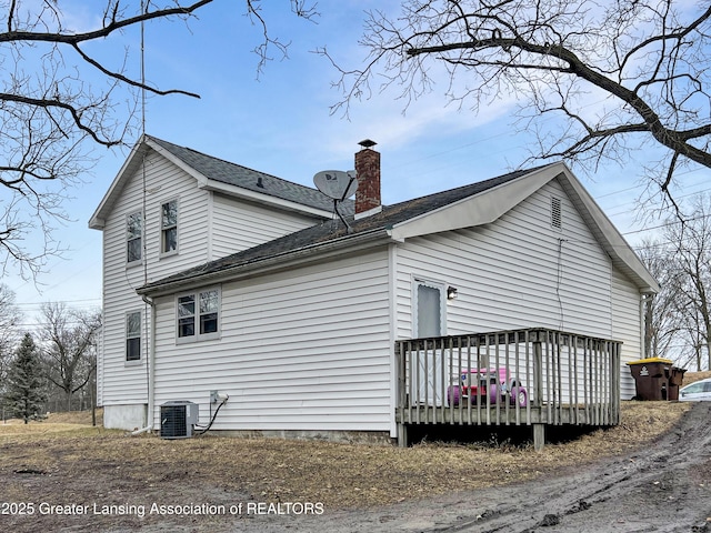 view of side of property with a chimney, a deck, and cooling unit