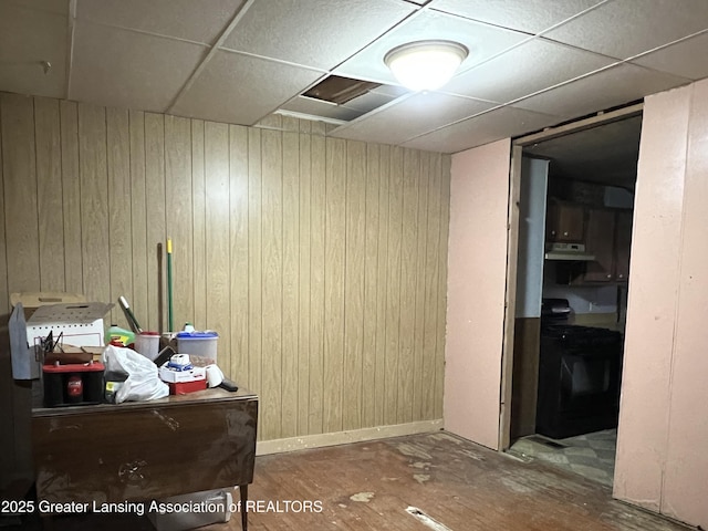 interior space with wood walls, a paneled ceiling, and baseboards