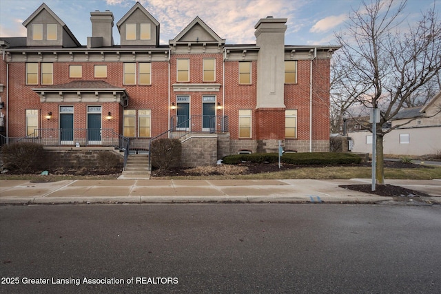 townhome / multi-family property featuring a chimney and brick siding