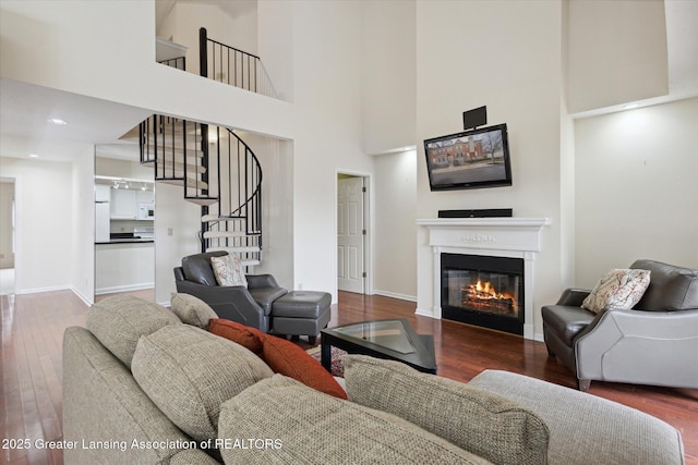 living room with baseboards, a glass covered fireplace, stairway, hardwood / wood-style floors, and recessed lighting