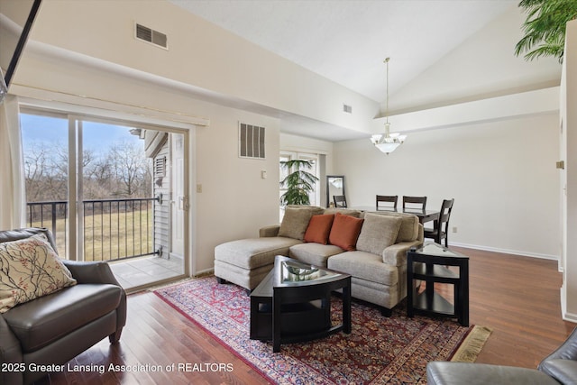 living room featuring high vaulted ceiling, wood finished floors, visible vents, and a notable chandelier