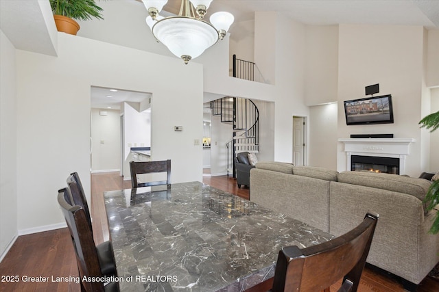 dining space with stairs, a glass covered fireplace, dark wood finished floors, and baseboards