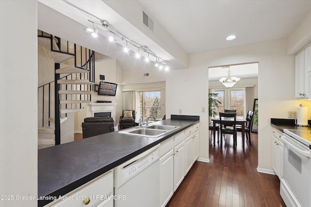 kitchen featuring white appliances, dark countertops, dark wood-type flooring, white cabinetry, and a sink