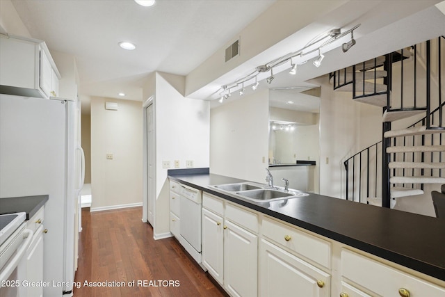 kitchen with dark countertops, visible vents, dark wood-type flooring, a sink, and white appliances