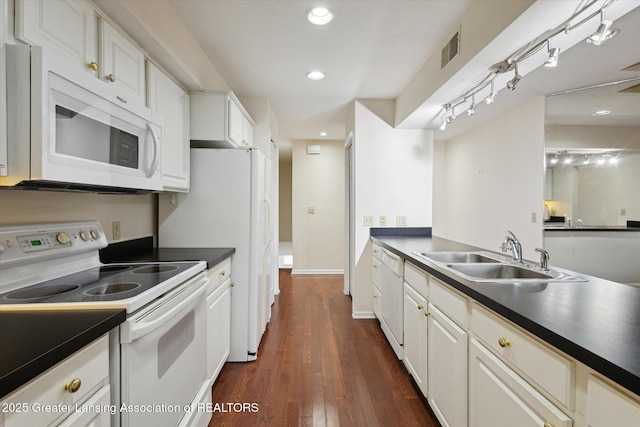 kitchen with white appliances, dark countertops, a sink, and visible vents